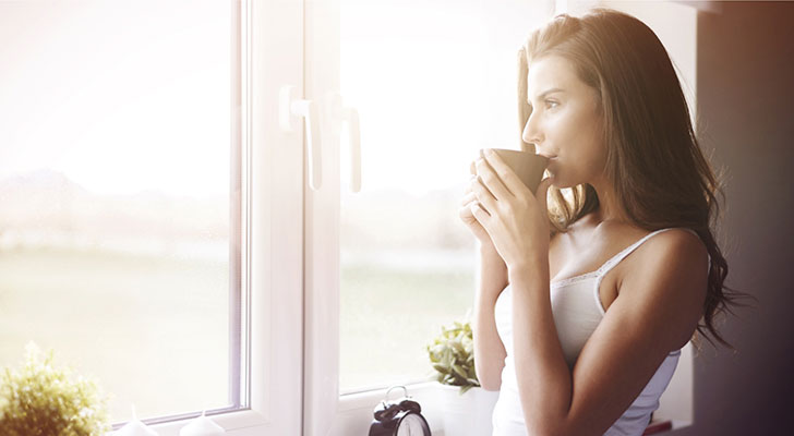 Vrouw drinkt koffie bij raam, want ze drinkt geen alcohol in Dry January