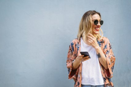 Smiling Blond Woman Using Smartphone, Blue Background