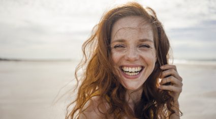 Portrait Of A Redheaded Woman, Laughing Happily On The Beach
