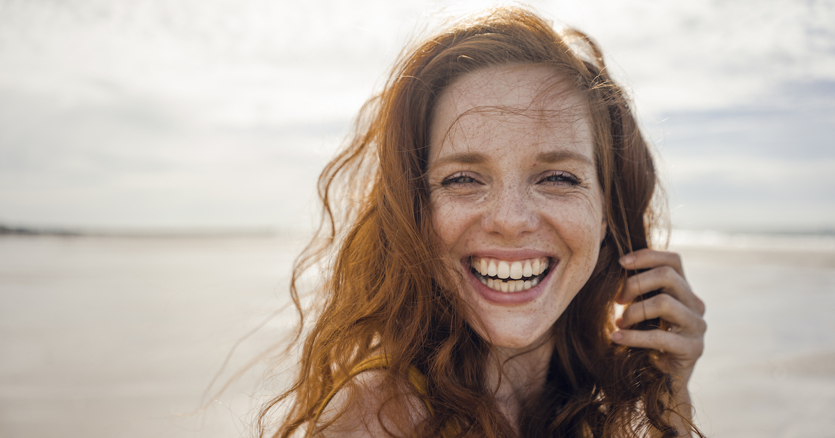 Portrait Of A Redheaded Woman, Laughing Happily On The Beach