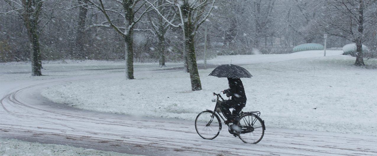 vrouw fietst door de sneeuw in amsterdam