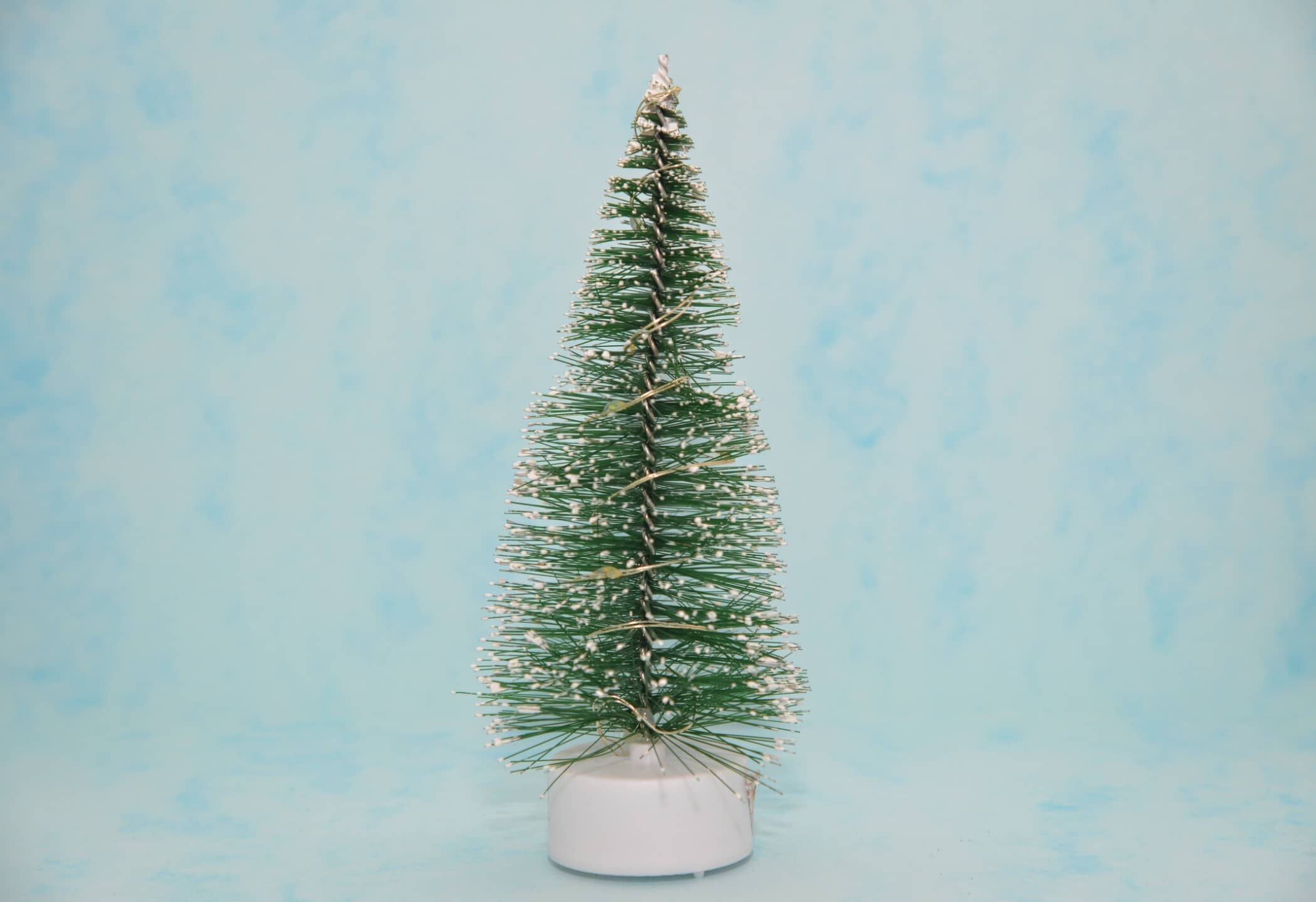 Kerstmusthaves: waxinelichtje met kerstboompje, blauwe achtergrond