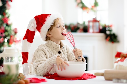 kerstrecepten: Jongetje met kerstmuts maakt deeg voor winterkoekje.
