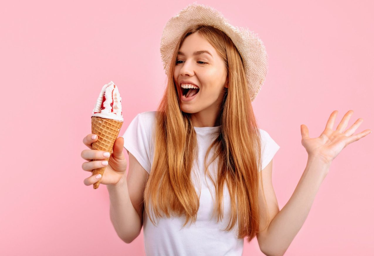 Keukenmachine Met Ijsmaker: vrouw eet ijsje, roze achtergrond