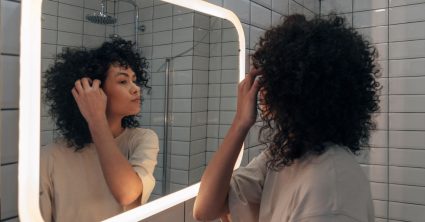 Vrouw kijkt in spiegel, ziet een haar dat grijs is.