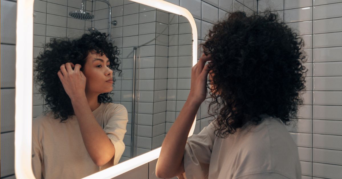 Vrouw kijkt in spiegel, ziet een haar dat grijs is.