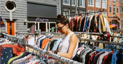 Vrouw tussen kleding kijken op een markt -Uitjes